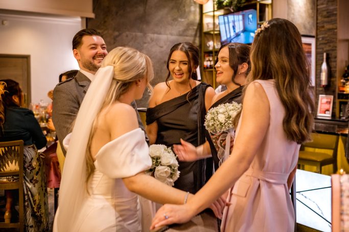 A group of women in formal attire celebrating at a wedding venue.